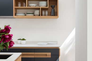 Example of a mid-sized trendy galley concrete floor and gray floor eat-in kitchen design in London with a drop-in sink, flat-panel cabinets, blue cabinets, solid surface countertops, white backsplash, an island and white countertops