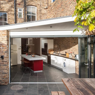 Kleine, Geschlossene Moderne Küche mit flächenbündigen Schrankfronten, weißen Schränken, Schieferboden, Kücheninsel und grauem Boden in London