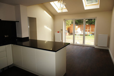 This is an example of a large contemporary u-shaped kitchen/diner in Cheshire with a submerged sink, flat-panel cabinets, black splashback and black appliances.