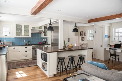 Kitchen - mid-sized traditional medium tone wood floor kitchen idea in Boston with a drop-in sink, recessed-panel cabinets, white cabinets, wood countertops, blue backsplash, ceramic backsplash, stainless steel appliances and an island