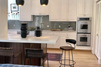 Example of a mid-sized trendy light wood floor and beige floor kitchen design in San Francisco with a drop-in sink, raised-panel cabinets, medium tone wood cabinets, quartz countertops, green backsplash, glass tile backsplash, stainless steel appliances, an island and white countertops
