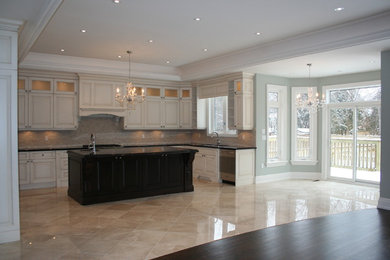 Photo of a medium sized traditional u-shaped enclosed kitchen in Toronto with a submerged sink, raised-panel cabinets, beige cabinets, granite worktops, porcelain flooring, an island, beige floors, black worktops, beige splashback, matchstick tiled splashback and stainless steel appliances.