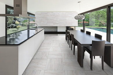 Example of a mid-sized minimalist single-wall porcelain tile eat-in kitchen design in Toronto with a drop-in sink, flat-panel cabinets, white cabinets, granite countertops, stainless steel appliances and an island