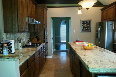 Zweizeilige, Mittelgroße Wohnküche mit Doppelwaschbecken, dunklen Holzschränken, Granit-Arbeitsplatte, bunter Rückwand, Küchengeräten aus Edelstahl, Keramikboden und Kücheninsel in Houston