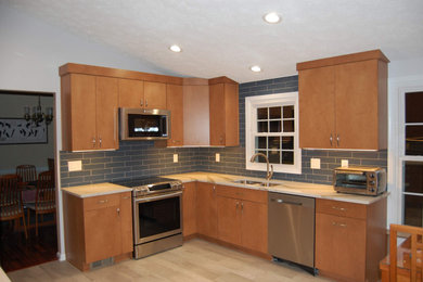 Mid-sized transitional l-shaped vinyl floor eat-in kitchen photo in DC Metro with a double-bowl sink, flat-panel cabinets, light wood cabinets, quartz countertops, blue backsplash, porcelain backsplash, stainless steel appliances and white countertops