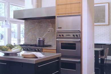 Diseño de cocina comedor contemporánea con armarios con paneles lisos, puertas de armario de madera clara y electrodomésticos de acero inoxidable