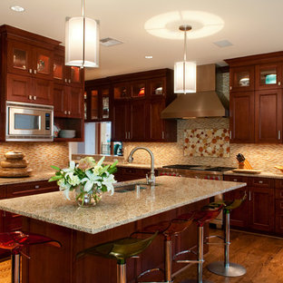 This is an example of a mid-sized country l-shaped eat-in kitchen in Dallas with a drop-in sink, shaker cabinets, medium wood cabinets, limestone benchtops, multi-coloured splashback, matchstick tile splashback, stainless steel appliances, light hardwood floors and with island.