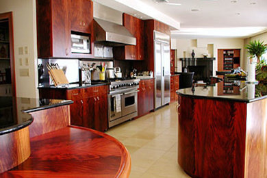 Diseño de cocina contemporánea grande con armarios con paneles lisos, puertas de armario de madera oscura, electrodomésticos de acero inoxidable, suelo de baldosas de terracota, suelo beige y una isla