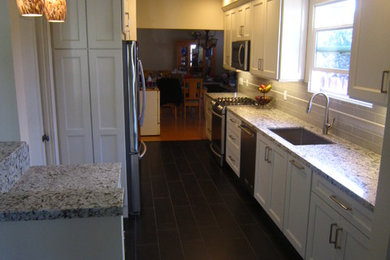 Small transitional galley porcelain tile and black floor kitchen photo in San Diego with a single-bowl sink, shaker cabinets, white cabinets, granite countertops, gray backsplash, ceramic backsplash and stainless steel appliances