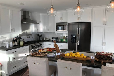 Inspiration for a large cottage l-shaped vinyl floor and brown floor eat-in kitchen remodel in San Luis Obispo with an undermount sink, shaker cabinets, white cabinets, quartzite countertops, white backsplash, subway tile backsplash, stainless steel appliances, an island and black countertops