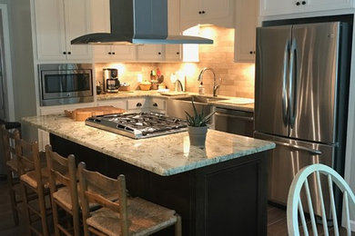 Inspiration for a large transitional l-shaped brown floor eat-in kitchen remodel in Birmingham with a farmhouse sink, recessed-panel cabinets, white cabinets, beige backsplash, stainless steel appliances and an island