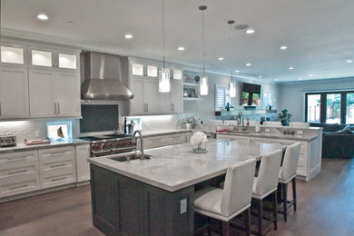 Example of a large transitional u-shaped light wood floor and brown floor eat-in kitchen design in San Francisco with an undermount sink, recessed-panel cabinets, white cabinets, marble countertops, white backsplash, ceramic backsplash, stainless steel appliances, an island and gray countertops