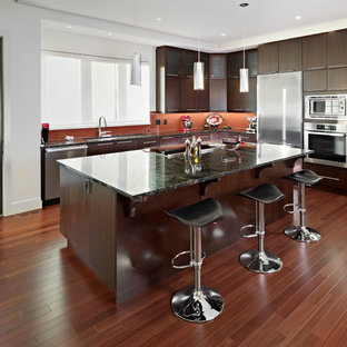 Inspiration for a contemporary l-shaped kitchen in Edmonton with an undermount sink, flat-panel cabinets, dark wood cabinets, orange splashback, glass sheet splashback and stainless steel appliances.