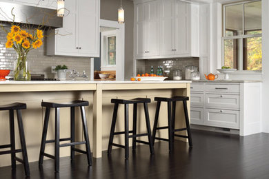Example of a mid-sized classic l-shaped dark wood floor eat-in kitchen design in New York with recessed-panel cabinets, dark wood cabinets, granite countertops, gray backsplash, glass tile backsplash and an island