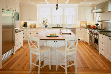 Example of a classic u-shaped kitchen design in Boston with wood countertops, recessed-panel cabinets, white cabinets, stone slab backsplash and stainless steel appliances
