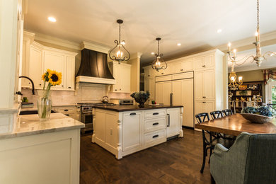 Example of a large arts and crafts u-shaped dark wood floor eat-in kitchen design in DC Metro with a farmhouse sink, beaded inset cabinets, distressed cabinets, granite countertops and stone tile backsplash