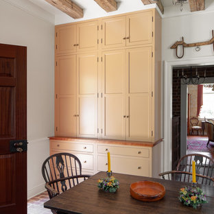 Imagen de cocina comedor lineal, campestre, pequeña, sin isla, con fregadero sobremueble, armarios estilo shaker, puertas de armario naranjas, encimera de madera, electrodomésticos de acero inoxidable, suelo de ladrillo, suelo marrón y encimeras naranjas