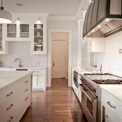 Elegant l-shaped kitchen photo in New York with recessed-panel cabinets, white cabinets, marble countertops, white backsplash, stone slab backsplash and paneled appliances