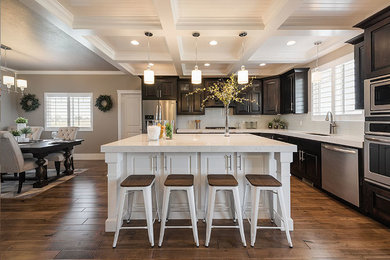 Inspiration for a mid-sized transitional l-shaped medium tone wood floor and brown floor eat-in kitchen remodel in Salt Lake City with dark wood cabinets, quartz countertops, white backsplash, subway tile backsplash, stainless steel appliances, an undermount sink, raised-panel cabinets and an island