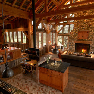 Design ideas for a large country u-shaped open plan kitchen in Philadelphia with a farmhouse sink, shaker cabinets, medium wood cabinets, soapstone benchtops, black splashback, stone slab splashback, black appliances, brick floors and with island.