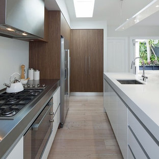 Immagine di una piccola cucina parallela contemporanea con elettrodomestici in acciaio inossidabile, top in acciaio inossidabile, ante lisce, ante bianche e paraspruzzi bianco