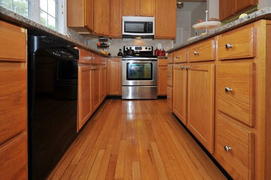 Example of a classic light wood floor kitchen design in Philadelphia with light wood cabinets, granite countertops, beige backsplash, ceramic backsplash and an island