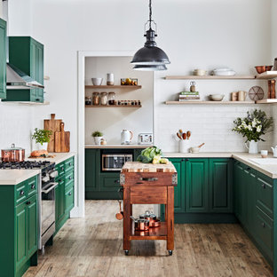 Design ideas for a transitional u-shaped kitchen in Melbourne with a drop-in sink, raised-panel cabinets, green cabinets, wood benchtops, white splashback, subway tile splashback, stainless steel appliances, medium hardwood floors, with island, brown floor and beige benchtop.