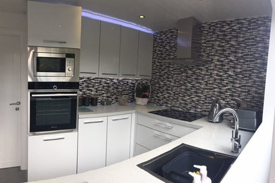 Photo of a medium sized contemporary enclosed kitchen in Glasgow with white cabinets, quartz worktops, stainless steel appliances, laminate floors and grey floors.