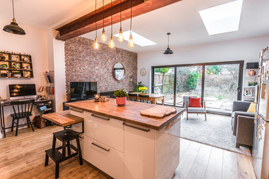 Large contemporary l-shaped kitchen/diner in Cardiff with beaded cabinets, white cabinets, wood worktops, light hardwood flooring, an island, brown floors and brown worktops.