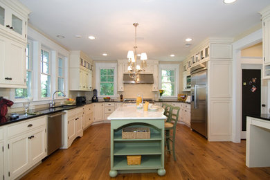 Example of a large trendy u-shaped medium tone wood floor eat-in kitchen design in DC Metro with a drop-in sink, an island, shaker cabinets, white cabinets, marble countertops, white backsplash and stainless steel appliances