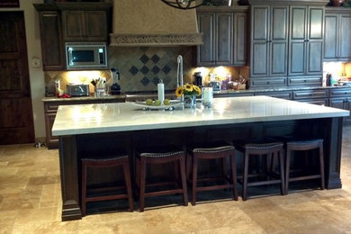 Example of a large classic l-shaped beige floor open concept kitchen design in Phoenix with raised-panel cabinets, dark wood cabinets, gray backsplash, stainless steel appliances and an island