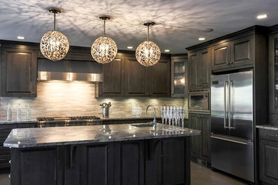 Example of an eat-in kitchen design in Sacramento with an island, recessed-panel cabinets, dark wood cabinets, marble countertops, beige backsplash and stainless steel appliances