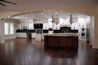 Example of a huge classic l-shaped eat-in kitchen design in Raleigh with raised-panel cabinets, granite countertops and two islands