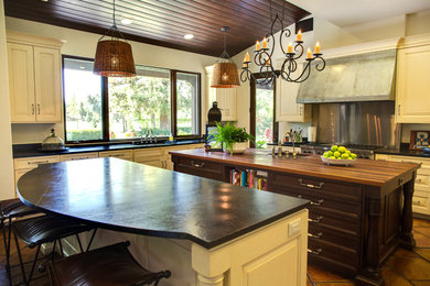 Example of a huge transitional l-shaped terra-cotta tile eat-in kitchen design in Los Angeles with a farmhouse sink, raised-panel cabinets, white cabinets, soapstone countertops, stainless steel appliances and two islands