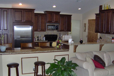 Example of a classic l-shaped eat-in kitchen design in Miami with an undermount sink, raised-panel cabinets, dark wood cabinets, granite countertops, beige backsplash and stainless steel appliances