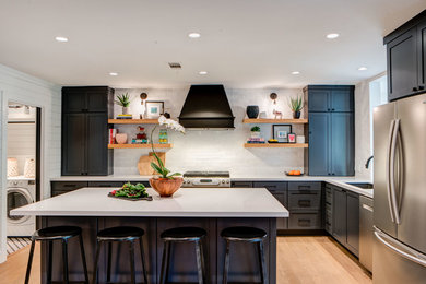 Mid-sized farmhouse brown floor and light wood floor kitchen photo in Austin with an undermount sink, shaker cabinets, blue cabinets, quartz countertops, white backsplash, terra-cotta backsplash, stainless steel appliances, white countertops and an island