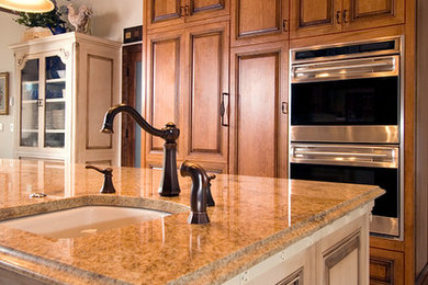 Eat-in kitchen - large traditional u-shaped ceramic tile eat-in kitchen idea in Albuquerque with a single-bowl sink, raised-panel cabinets, medium tone wood cabinets, granite countertops, brown backsplash, ceramic backsplash, stainless steel appliances and an island