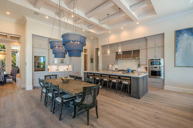 Open concept kitchen - coastal l-shaped light wood floor and brown floor open concept kitchen idea in Other with stainless steel appliances, an island, recessed-panel cabinets and gray cabinets