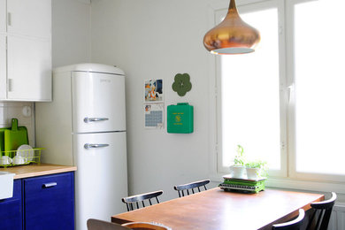 Modelo de cocina comedor bohemia con armarios con paneles lisos, puertas de armario azules y electrodomésticos blancos