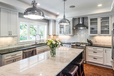 Inspiration for a large transitional u-shaped medium tone wood floor and brown floor eat-in kitchen remodel in Other with an undermount sink, shaker cabinets, white cabinets, quartz countertops, gray backsplash, marble backsplash, stainless steel appliances and an island