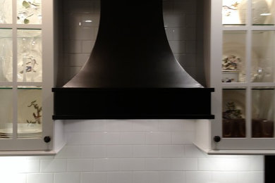 Modelo de cocina tradicional renovada con armarios estilo shaker, puertas de armario blancas, encimera de granito, salpicadero de azulejos tipo metro y electrodomésticos negros