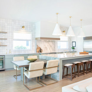 This is an example of a large beach style l-shaped eat-in kitchen in Miami with a single-bowl sink, shaker cabinets, green cabinets, quartzite benchtops, multi-coloured splashback, stone slab splashback, stainless steel appliances, porcelain floors, with island, grey floor and multi-coloured benchtop.