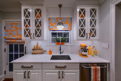 Kleine Klassische Küche mit Unterbauwaschbecken, profilierten Schrankfronten, weißen Schränken, Küchenrückwand in Weiß, Küchengeräten aus Edelstahl und braunem Holzboden in New York