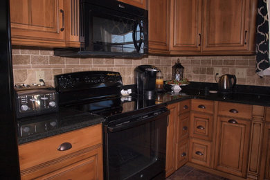 Example of a transitional ceramic tile eat-in kitchen design in Other with beige backsplash, stone tile backsplash and black appliances