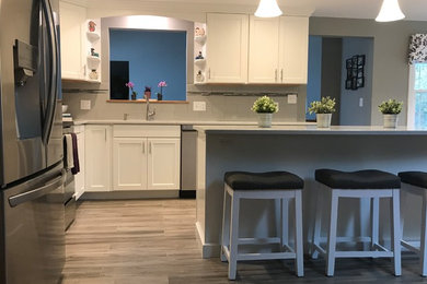 Example of a mid-sized transitional l-shaped porcelain tile and gray floor open concept kitchen design in Boston with a single-bowl sink, flat-panel cabinets, white cabinets, quartz countertops, gray backsplash, subway tile backsplash, stainless steel appliances, an island and white countertops