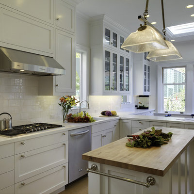 Example of a mid-sized classic l-shaped cork floor eat-in kitchen design in San Francisco with stainless steel appliances, subway tile backsplash, white cabinets, solid surface countertops, white backsplash, an island, a drop-in sink and shaker cabinets