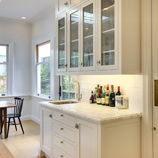 Design ideas for a large traditional l-shaped kitchen/diner in San Francisco with metro tiled splashback, a submerged sink, glass-front cabinets, white cabinets, white splashback, marble worktops, cork flooring, stainless steel appliances and an island.