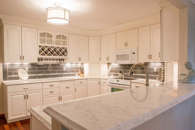 Example of a mid-sized transitional u-shaped medium tone wood floor eat-in kitchen design in Cedar Rapids with white cabinets, quartzite countertops, gray backsplash, porcelain backsplash, white appliances and no island