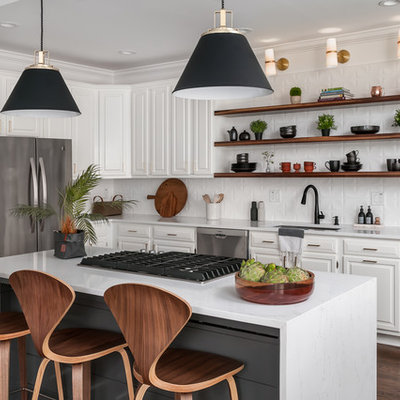 Inspiration for a mid-sized transitional l-shaped dark wood floor and brown floor kitchen remodel in Atlanta with raised-panel cabinets, white cabinets, white backsplash, stainless steel appliances, an island, white countertops, a drop-in sink, quartzite countertops and ceramic backsplash