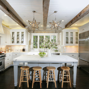Immagine di una cucina ad U chic con ante di vetro, elettrodomestici in acciaio inossidabile, top in marmo, ante bianche e paraspruzzi bianco